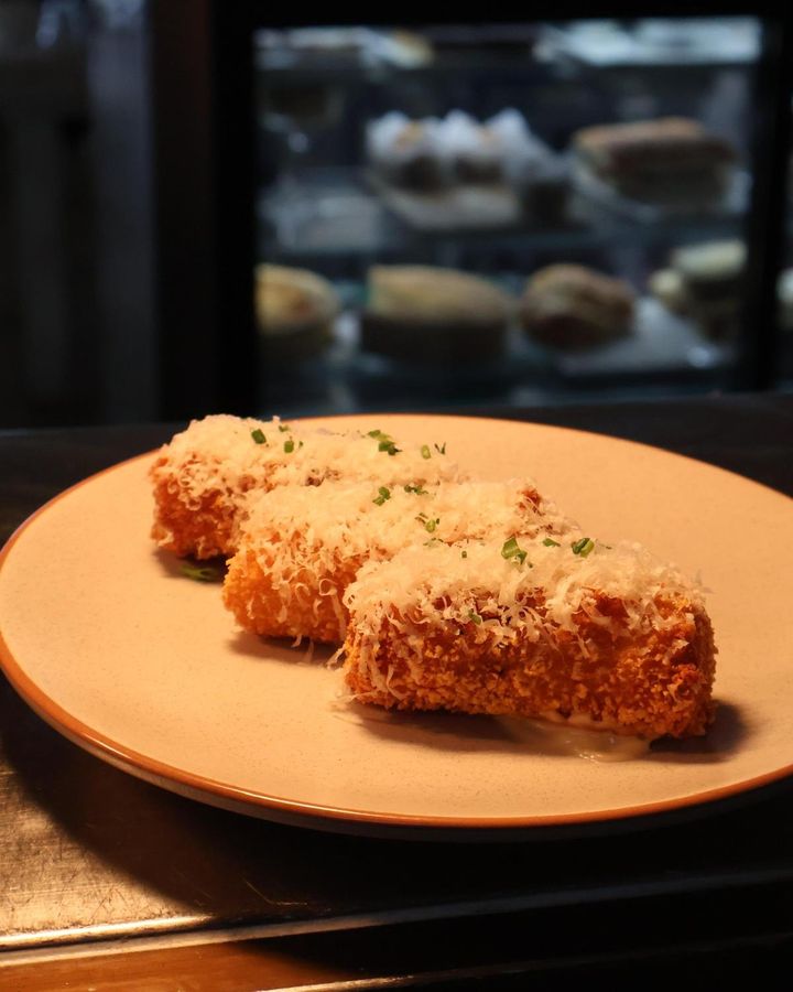 Featured image for “Golden, crispy, and packed with cheesy goodness—our Cheesy Potato Croquette is topped with a sprinkle of parmesan and served with garlic aioli for that perfect dip.”